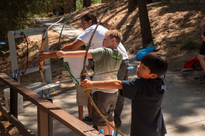 Three campers getting ready to shoot their bow and arrow at camp 