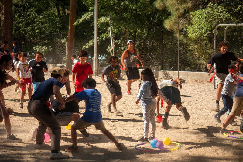 A group of campers playing an outdoor game in the sand at summer camp