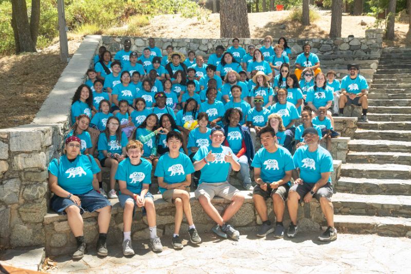 Group photo of around 55 campers and staff at Jay Nolan Camp. All are wearing blue t-shirts.