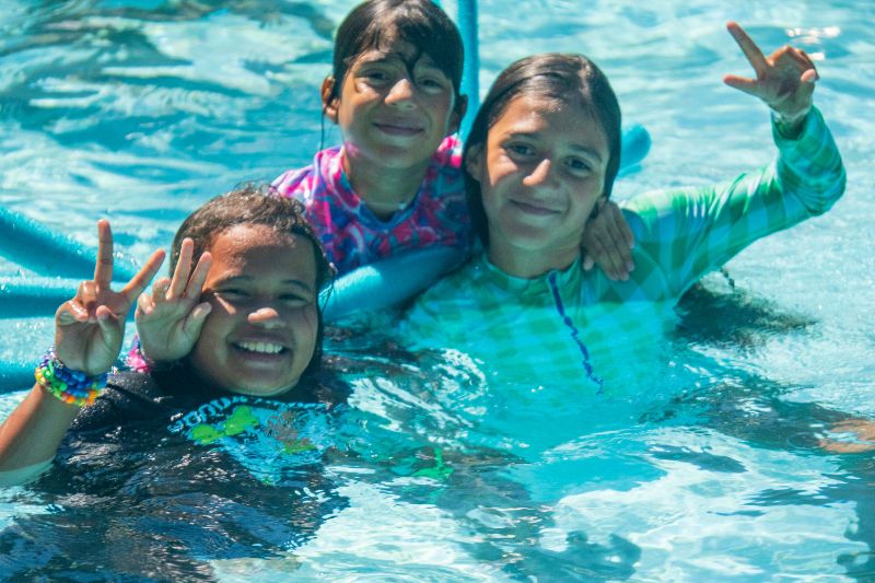 Three kids swimming in a swimming pool
